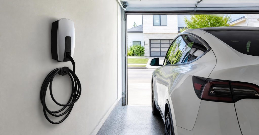 Wall-mounted EV charger installed in a clean residential garage with the cable coiled on its hook.